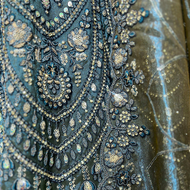 Close-up of blue shimmer fabric with ornate gold and silver embroidery