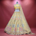 Yellow net patchwork lehenga with pastel embroidered tiers and lace hem