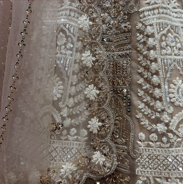 Close-up of ivory net lehenga: antique gold cutdana, pearl flowers and sequin drops