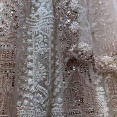 Close-up of off white net lehenga: white pearl clusters, dhaga motifs and gold sequin drops