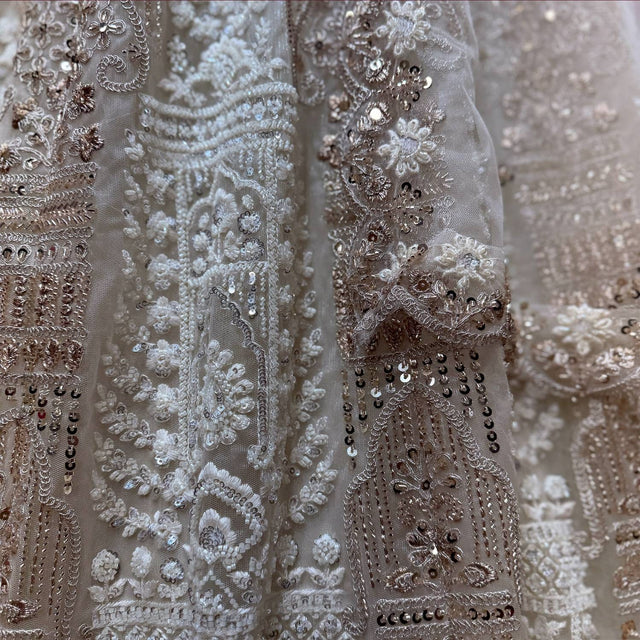Close-up of off white net lehenga: white pearl clusters, dhaga motifs and gold sequin drops