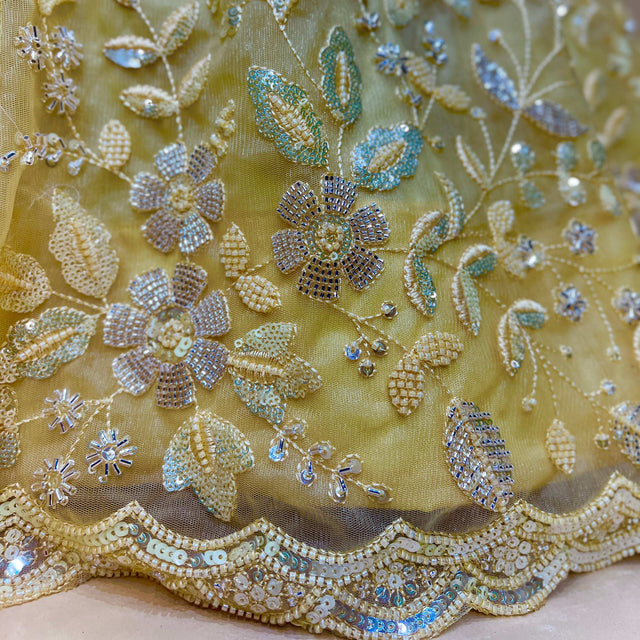 Yellow lehenga fabric with blue and silver beaded floral motifs and lace border