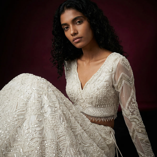 Off-white beaded blouse with V-neck, ornate embroidery, and fringe at hem
