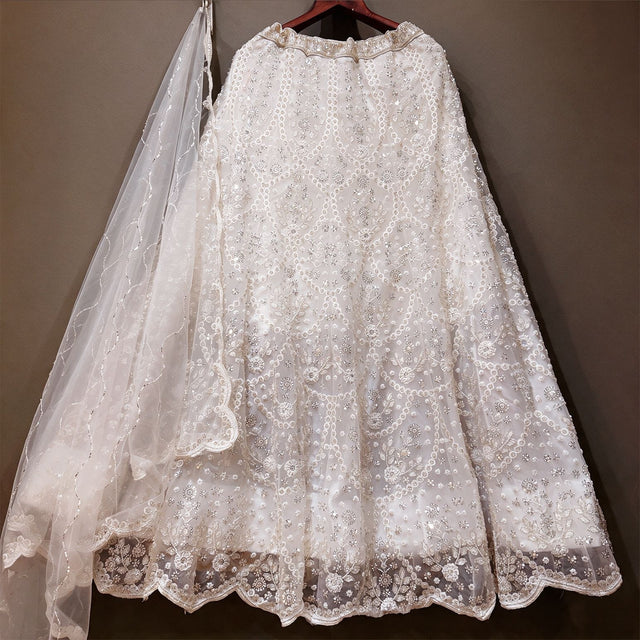 White beaded net lehenga skirt with scalloped hem and sequin net dupatta on hanger