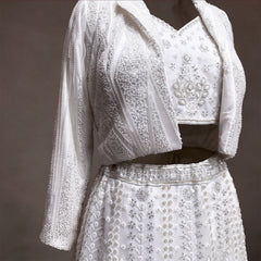 Close-up of pearl and sequin striped beaded jacket, handwork blouse and beaded waistband on white lehenga