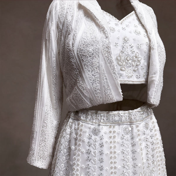 Close-up of pearl and sequin striped beaded jacket, handwork blouse and beaded waistband on white lehenga