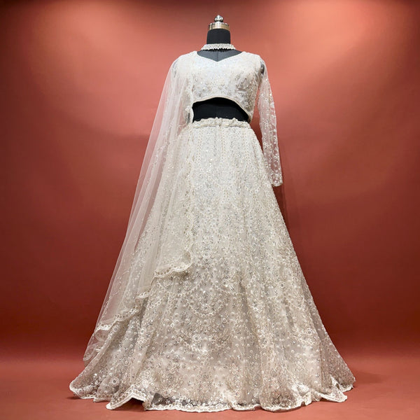 White beaded net lehenga set with full-sleeve blouse and dupatta on mannequin