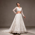White net lehenga with pearl and sequin handwork, sheer full-sleeve blouse and trailing net dupatta, worn