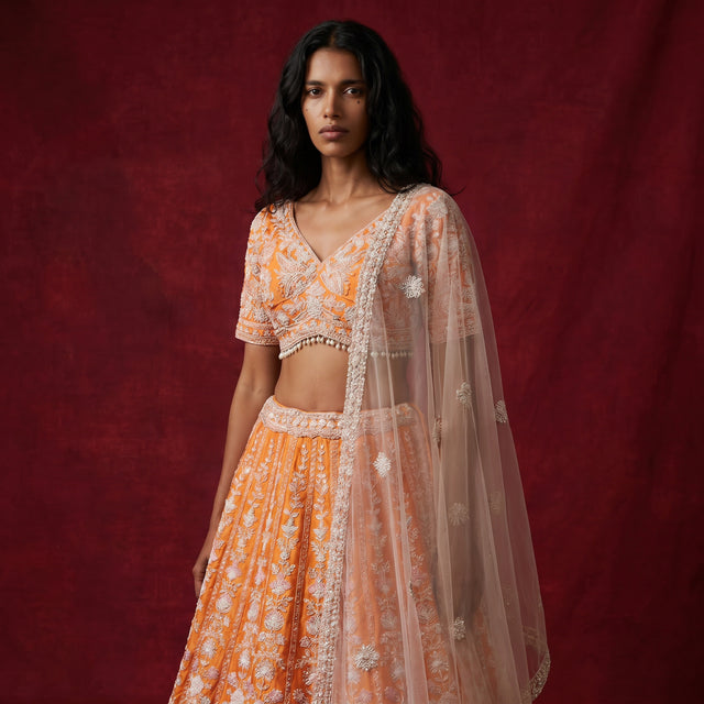 Orange lehenga with silver beadwork, short-sleeve blouse, and sheer draped dupatta