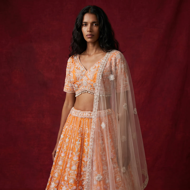 Orange lehenga with silver beadwork, short-sleeve blouse, and sheer draped dupatta