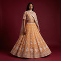 Beaded orange lehenga skirt with silver embroidery and sheer dupatta over shoulders