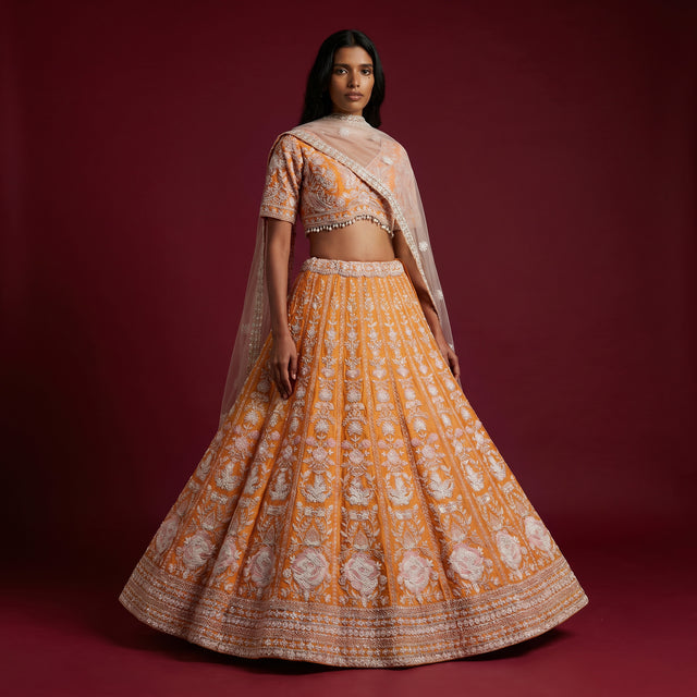 Beaded orange lehenga skirt with silver embroidery and sheer dupatta over shoulders