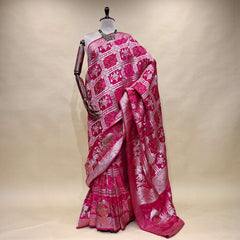 Rani pink satin silk saree with zari-patterned pallu and ornate border, draped