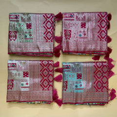Set of folded patola-style silk sarees with teal and pink geometric prints, magenta borders
