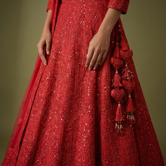 Red sequined lehenga skirt with dense embroidery and tassel potli on side
