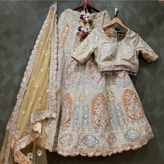 Ivory lehenga set with fitted blouse, ornate embroidered bands, and sheer embellished dupatta