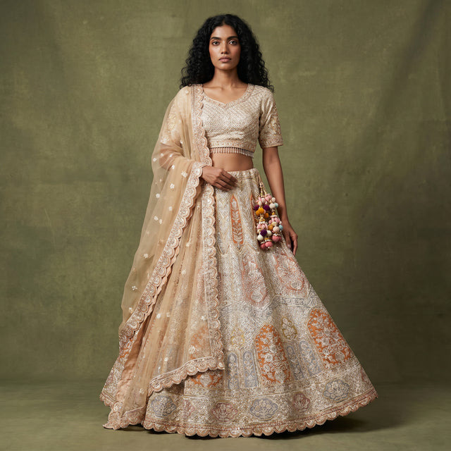 Ivory bridal lehenga with embellished blouse, tiered skirt, and sheer dupatta
