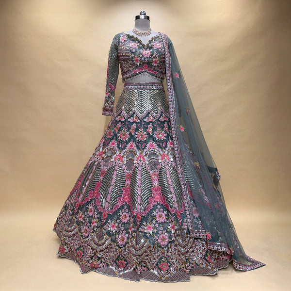Embroidered lehenga on mannequin with floral motifs, gray-blue base, pink and silver trim