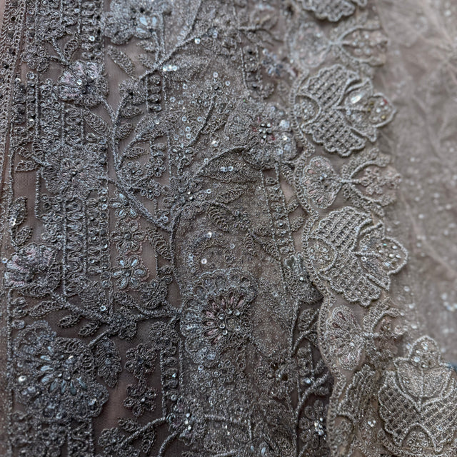 Close-up of silver net embroidery with beadwork and floral motifs, sheer fabric panel
