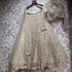 Ivory net cutdana lehenga, blouse and dupatta on hanger