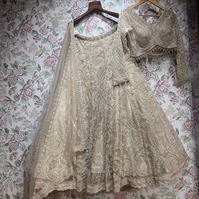 Ivory net cutdana lehenga, blouse and dupatta on hanger