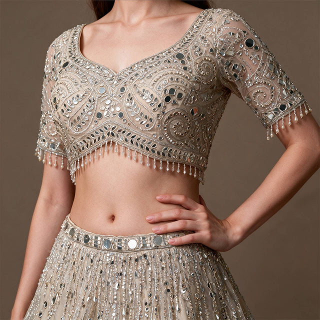 Close-up of leaf and spiral mirror work blouse with pearl drops and mirror waistband on champagne lehenga