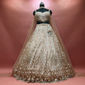 Champagne gold sequin and bead lehenga on a mannequin with sweetheart blouse, diamond lattice skirt, scalloped embellished hem and long net dupatta trailing behind