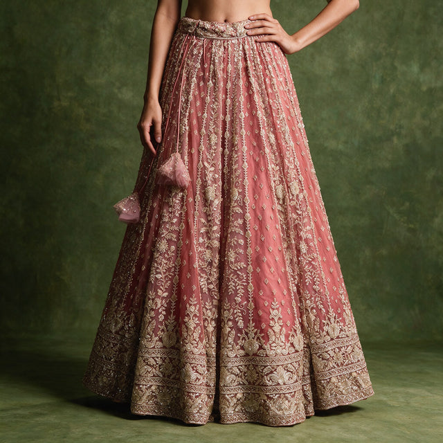Close-up of the dusty rose pink lehenga skirt with gold cutdana and pearl vines, a deep embroidered border and pink tassel latkans at the waist