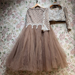 Mocha brown net fish cut lehenga and full-sleeve embroidered blouse on hangers against floral wallpaper