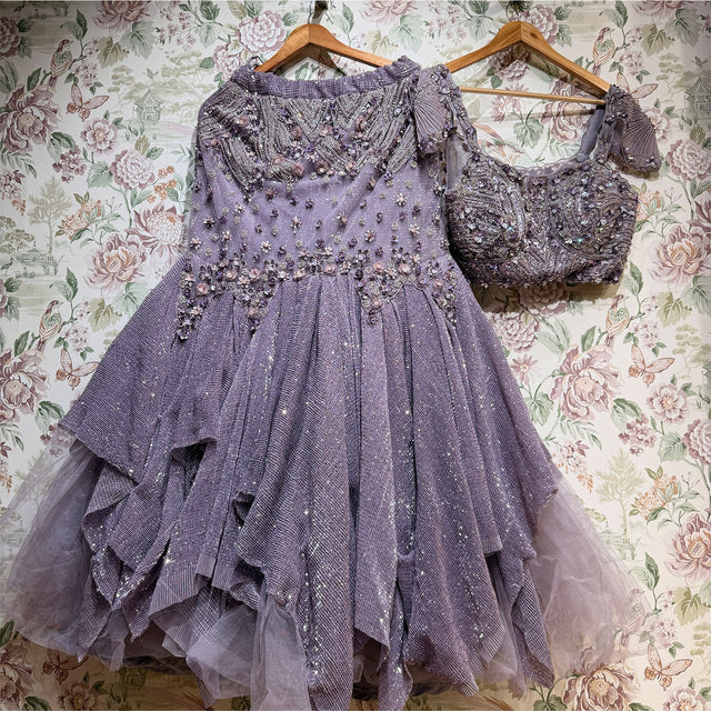 Mauve lavender net fish cut lehenga and bralette blouse on hangers against floral wallpaper, showing the beaded yoke and ruffle tiers