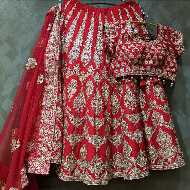 Red lehenga skirt and blouse set with heavy gold zari motifs, decorative border hem