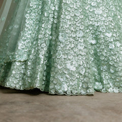 Close-up of pista green net lehenga hem with dense sequin florets and scalloped edge