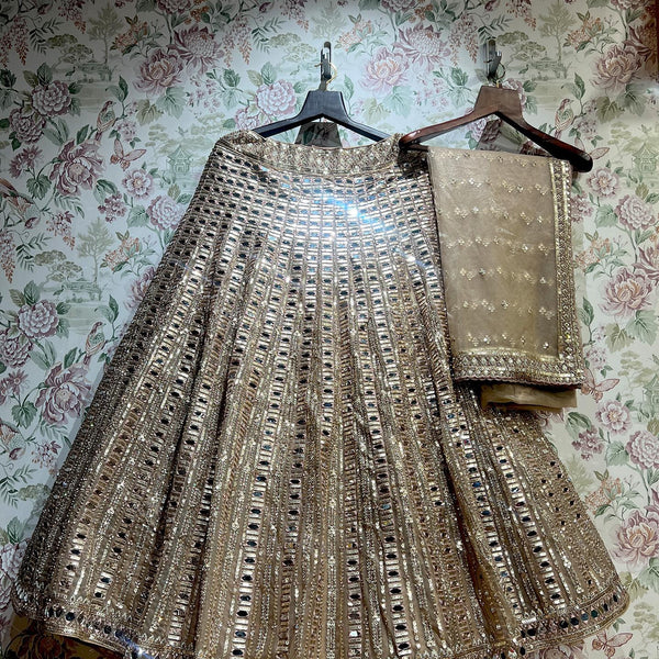 Ivory-gold net mirror lehenga and blouse set on hangers
