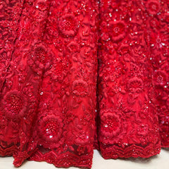 Red 3D floral moti and cutdana embroidery on lehenga fabric, close-up