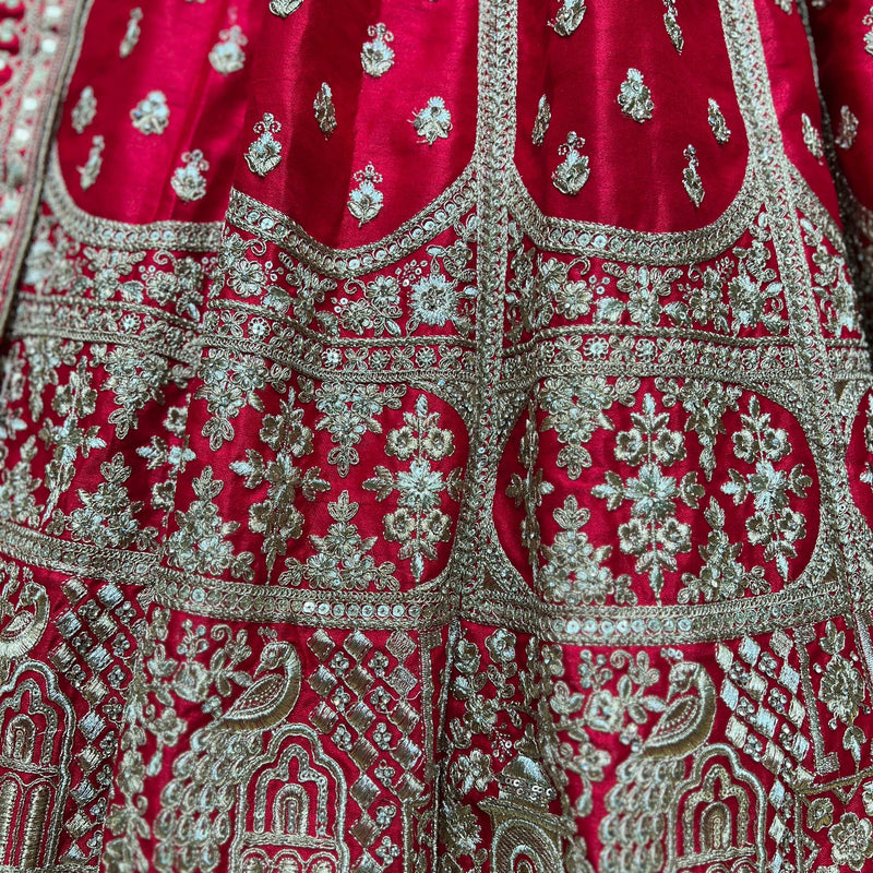 Close-up of red lehenga fabric with intricate silver and green floral embroidery