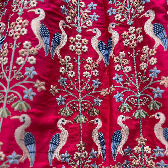 Magenta silk lehenga fabric with blue and white peacock motifs and floral embroidery