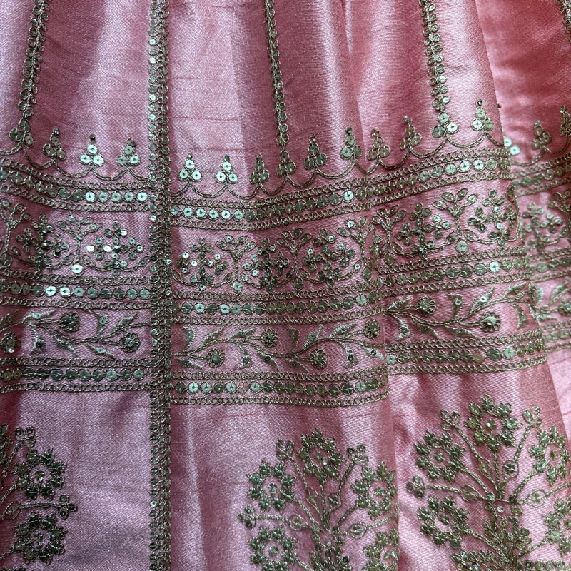 Close-up of pink raw silk lehenga fabric with ornate silver and teal beaded border