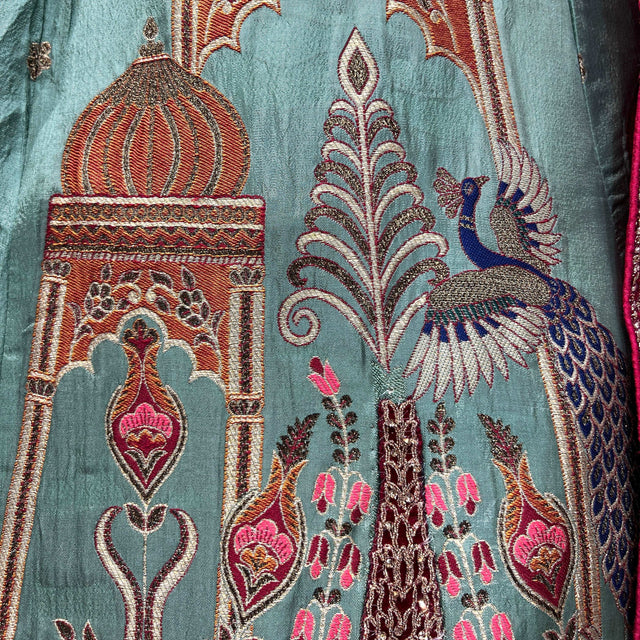 Teal lehenga fabric close-up with peacock and floral motifs in maroon, gold, and pink