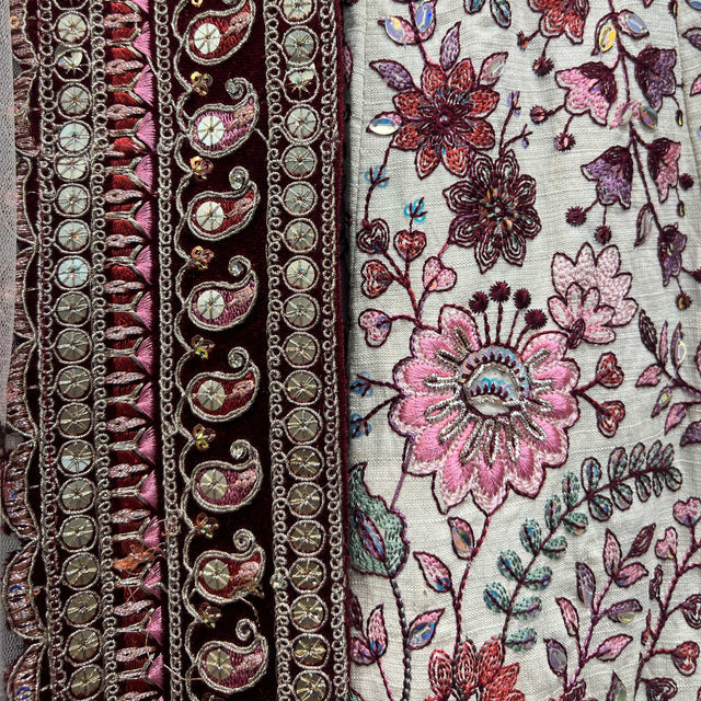 Embroidered fabric detail: ivory ground with dark maroon borders and florals