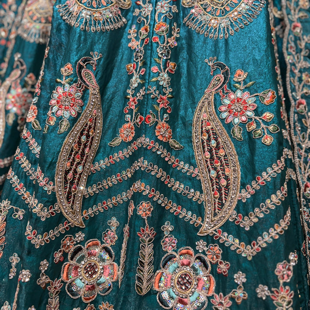 Teal fabric with dense multicolor floral and paisley embroidery, close-up