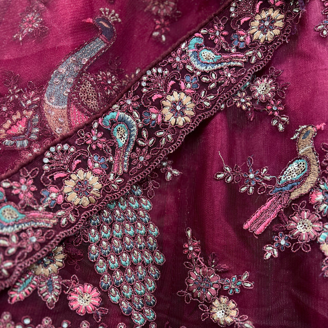 Maroon net fabric close-up with ornate multicolor floral and paisley embroidery