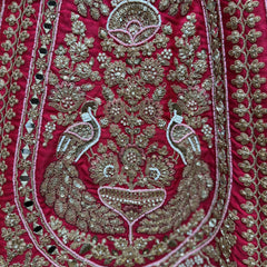 Close-up of rani pink lehenga fabric with detailed metallic thread and beadwork