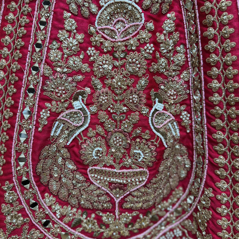 Close-up of rani pink lehenga fabric with detailed metallic thread and beadwork