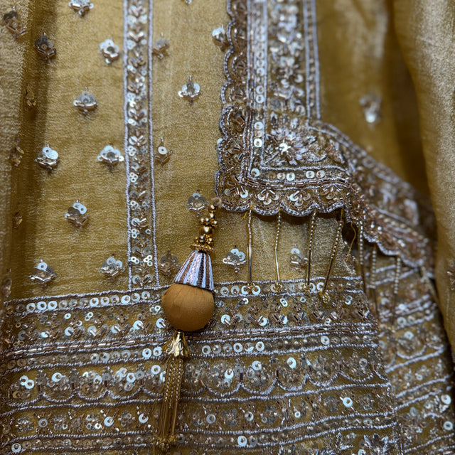Somber yellow lehenga bodice close-up with silver mirrorwork, sequins, and beaded trim