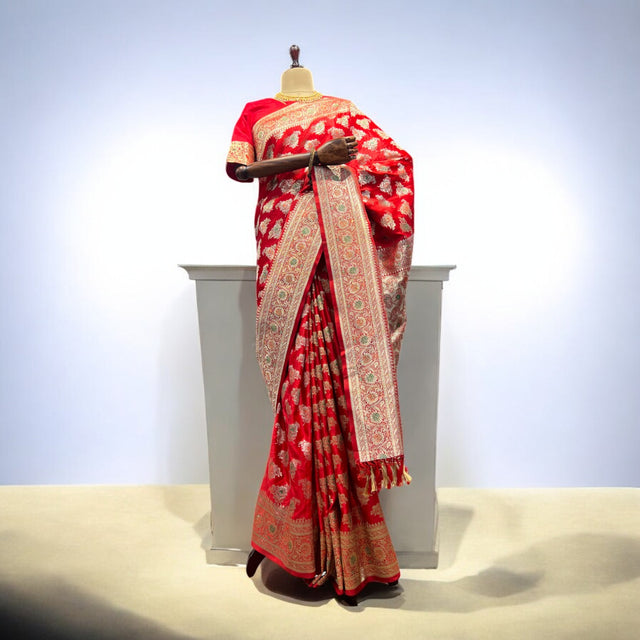 Red patterned saree with gold zari border, draped on mannequin