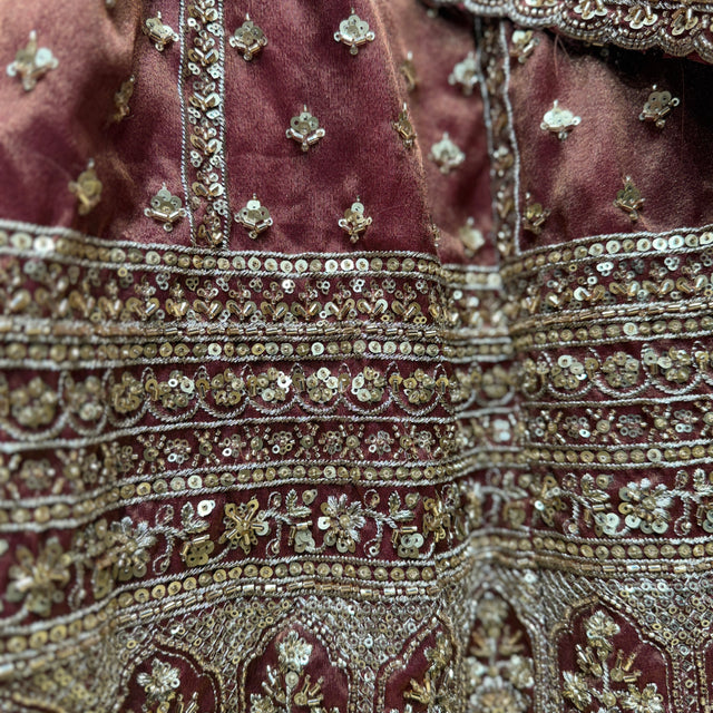 Close-up of rust-brown fabric with gold-tone sequins, beads, and ornamental bands