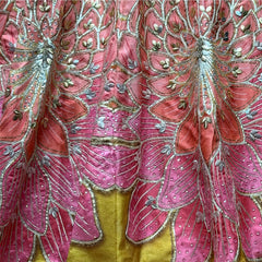 Close-up of the lehenga hem with coral and pink lotus-petal fans outlined in gold over a mustard silk border