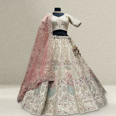 Ivory raw silk lehenga with pastel pink and mint embroidery on a mannequin, with a pink embroidered net dupatta and beaded latkan