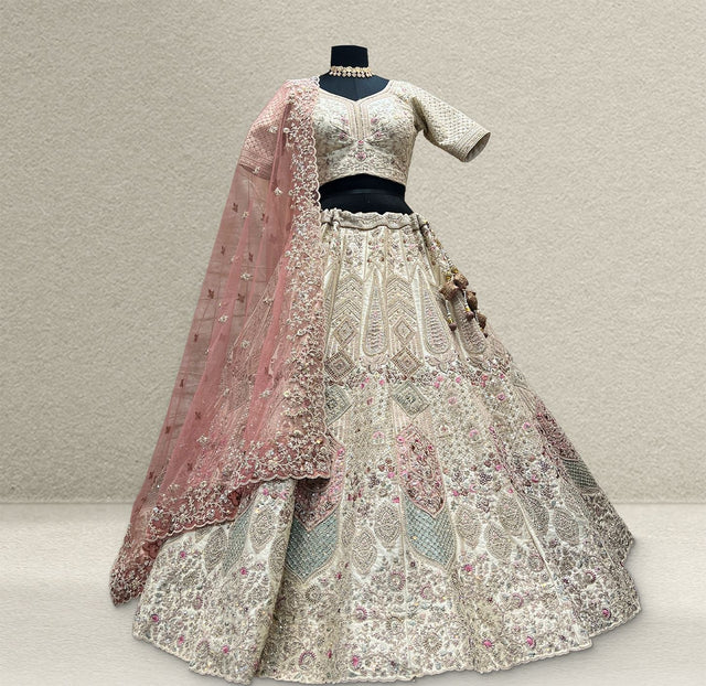 Ivory raw silk lehenga with pastel pink and mint embroidery on a mannequin, with a pink embroidered net dupatta and beaded latkan