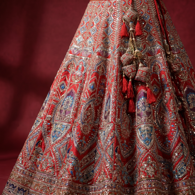 Red bridal lehenga skirt with detailed embroidered border and tassels